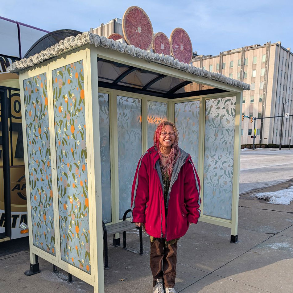 Young woman wearing glasses smiling at camera posing inside a bus shelter