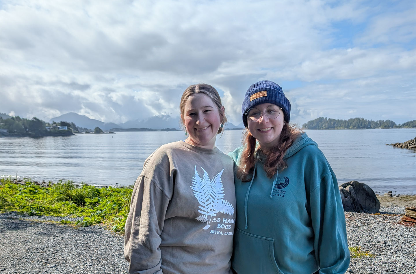 University of Akron students stand along the waterfront in Sitka, Alaska with mountains and the harbor in the background.