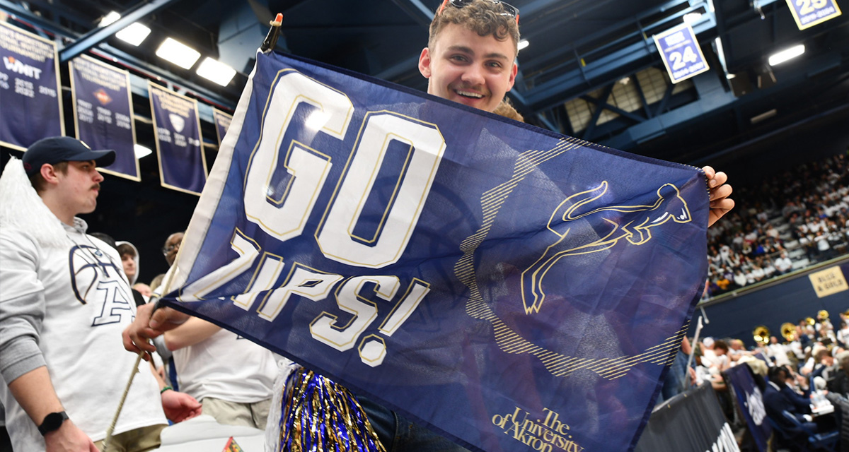 Student holding Go Zips banner at a basketball game